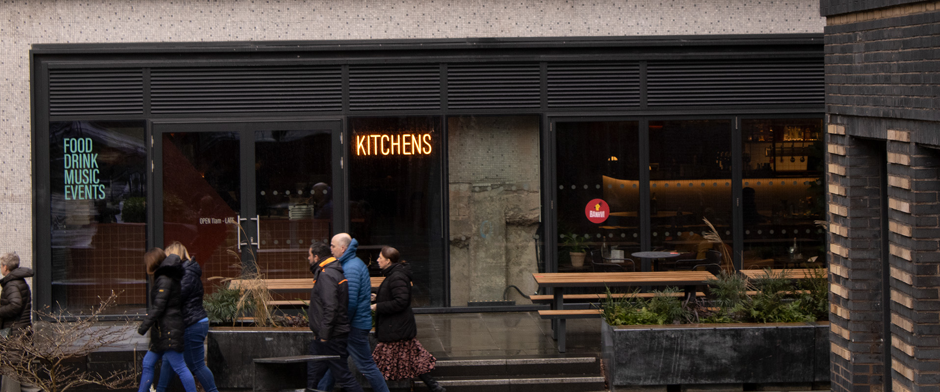 Outdoor shot of New Century Kitchen showcasing the external signage and window graphics